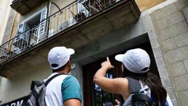 Dos inspectores de pisos turísticos del Ayuntamiento de Barcelona señalan un piso desde la calle / CG