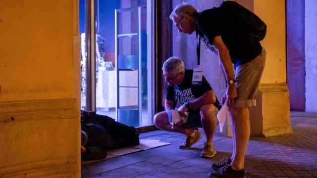 Dos voluntarios de Arrels se interesan por una persona sin hogar en Barcelona / KIKE RINCÓN - EUROPA PRESS
