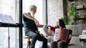 Un hombre y su nieta practican son sus intrumentos musicales / PEXELS