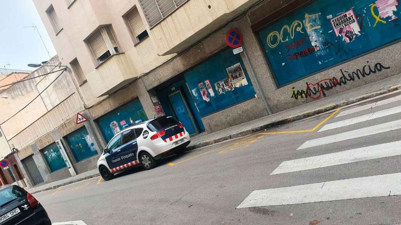 Imagen de un coche de Mossos d'Esquadra ante un local vacío para evitar su okupación / CG