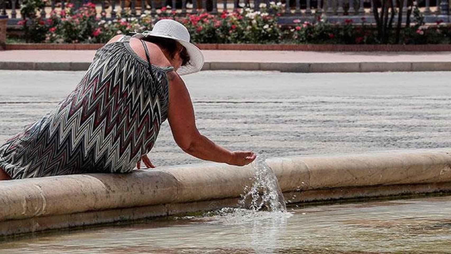 Una mujer se refresca en la plaza de España de Sevilla durante la ola de calor, que ha dejado cinco muertos en España / EFE