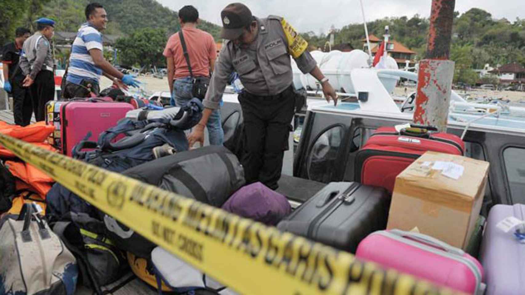 Un agente de policía recoge el equipaje de los pasajeros del bote que estalló en Bali (Indonesia) / EFE