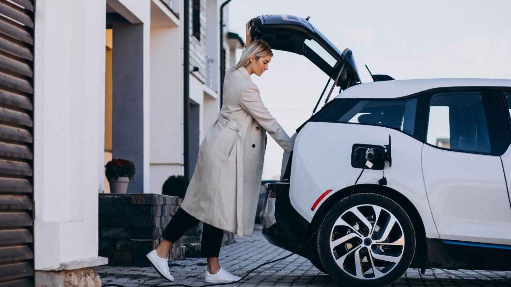 Una mujer carga su coche eléctrico / FREEPIK