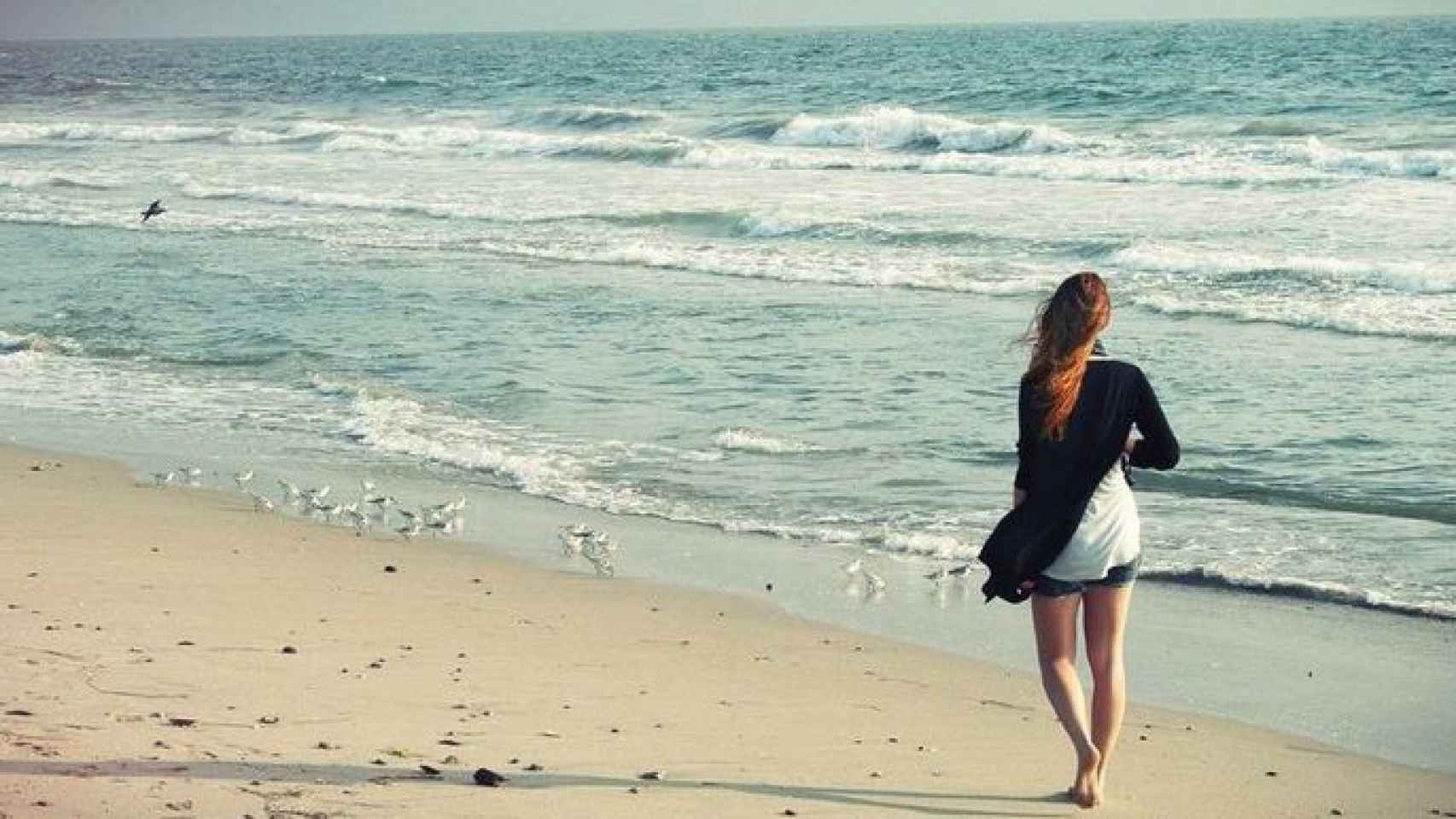 Una mujer camina por la playa / CD