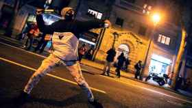 Un joven lanza una botella durante la octava noche de disturbios en Barcelona por la detención de Hasél / EFE