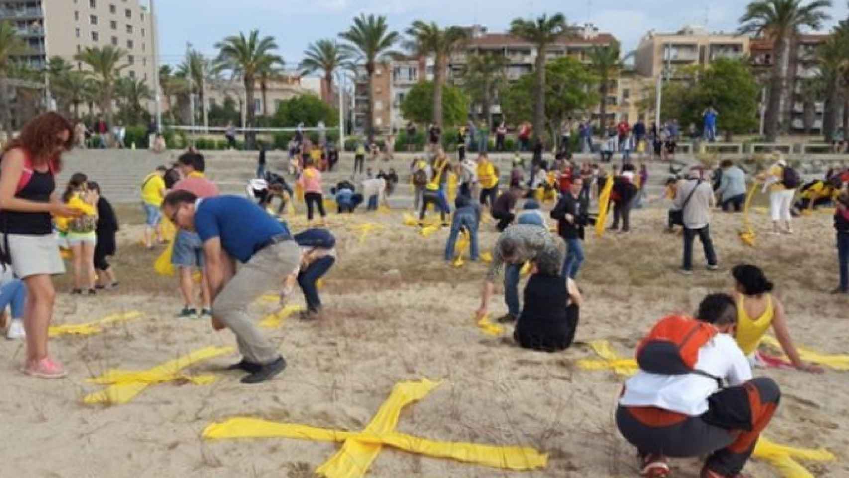 Miembros de los CDR colocando toallas amarillas en forma de cruz en la playa de Mataró / TWITTER