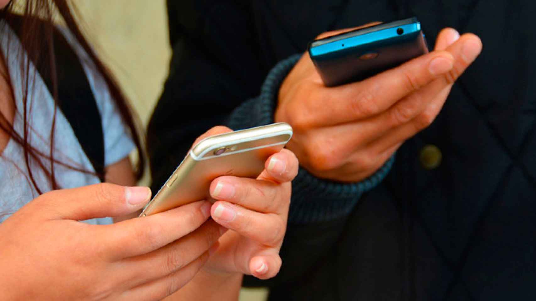 Dos adolescentes con sus móviles en la mano