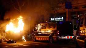 Varios furgones de Mossos delante de una barricada en llamas en Cataluña / EFE