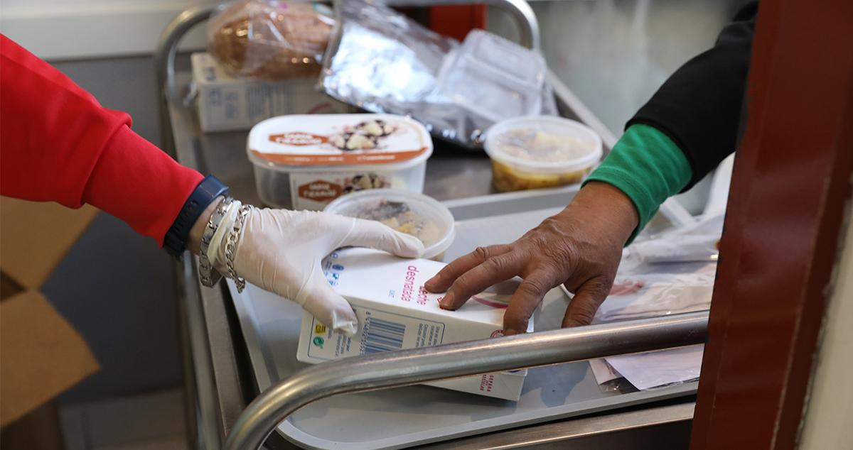 Un voluntario dándole comida a una persona en el reparto diario de alimentos / EP