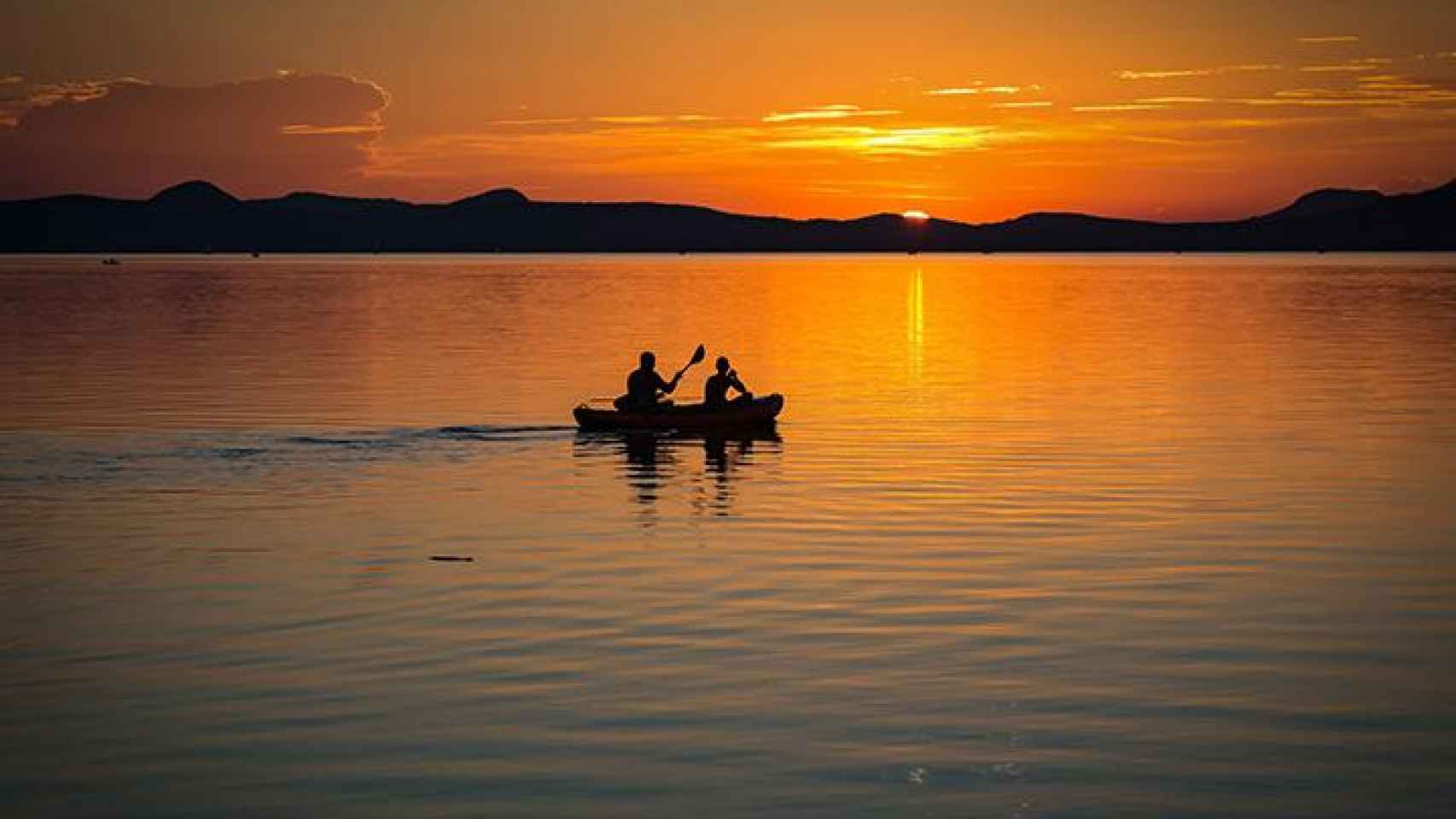 Dos personas disfrutan del atardecer en una barca de remo inflables en un lago / PEXELS