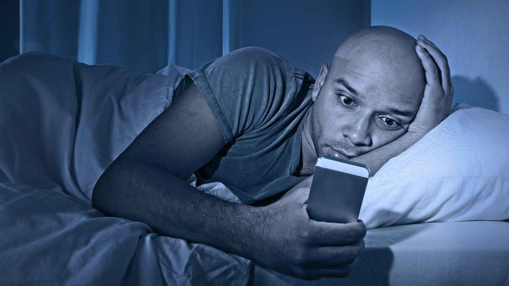 Una persona utilizando el teléfono móvil en la cama. Dormir tarde aumenta el riesgo de morir según un estudio
