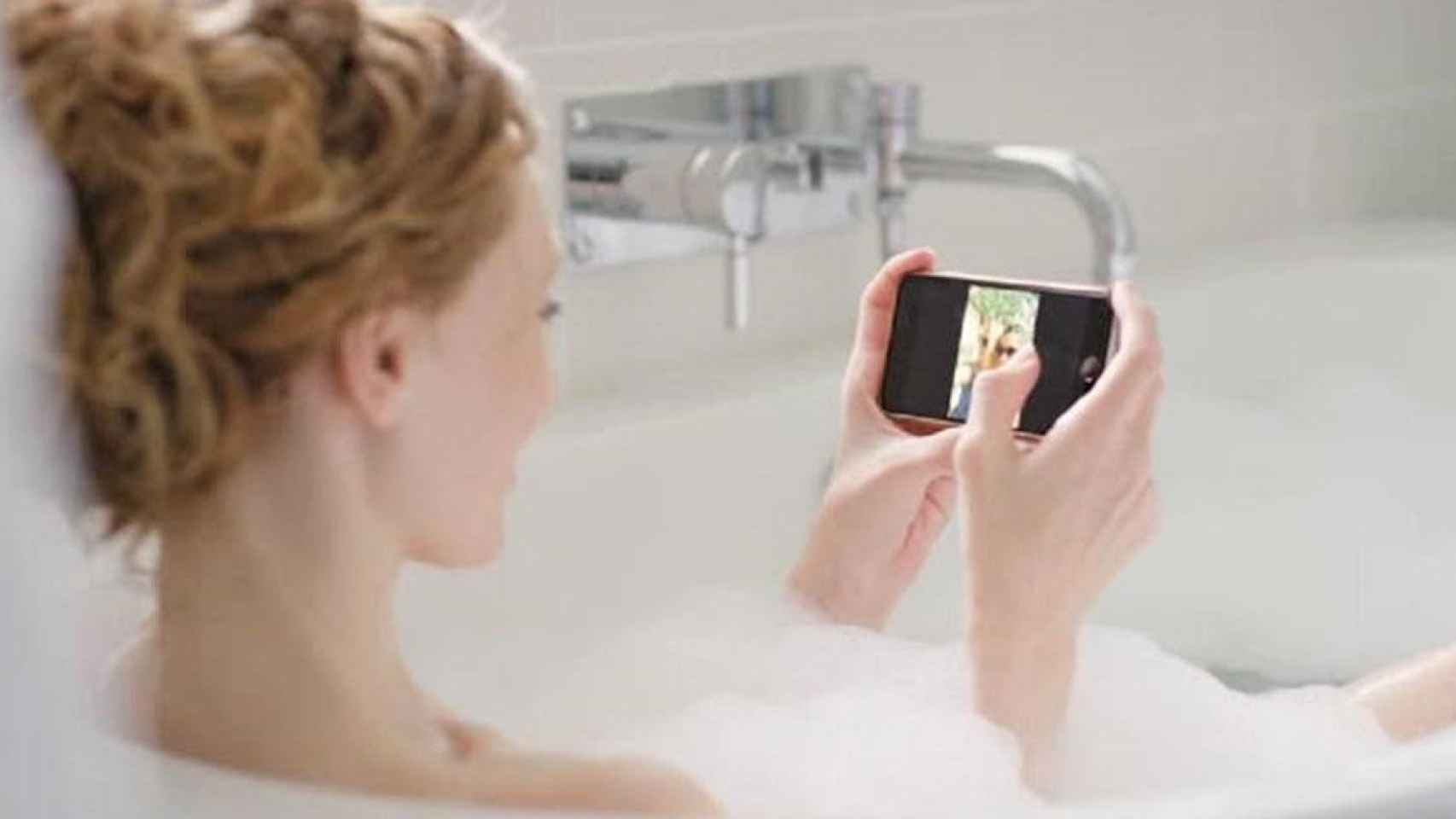 Una joven mira su móvil en la bañera