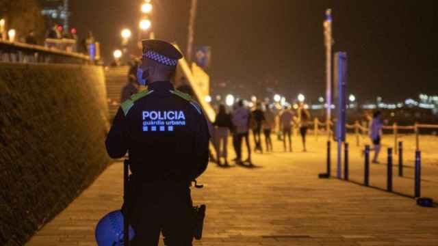 Un agente de la Guardia Urbana vigila la playa de la Barceloneta, donde han desalojado a varias personas en la primera noche del cierre de nuevo del ocio nocturno / Lorena Sopêna (EP)