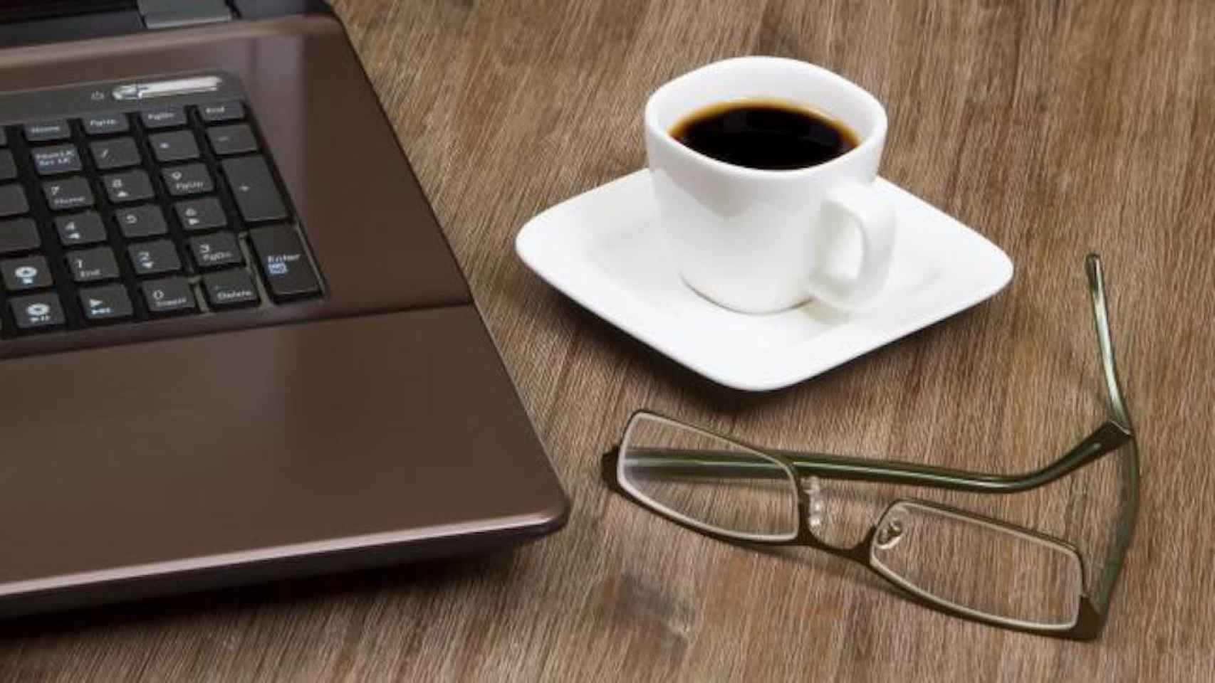 Una foto de archivo de una taza de café junto a un ordenador