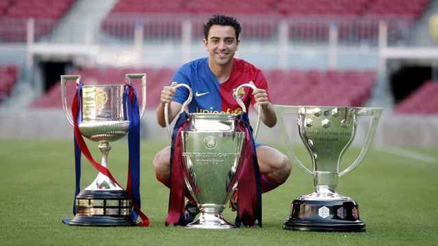 Xavi Hernàndez con los tres títulos que cosechó el FC Barcelona en la temporada 2008-09 / EFE