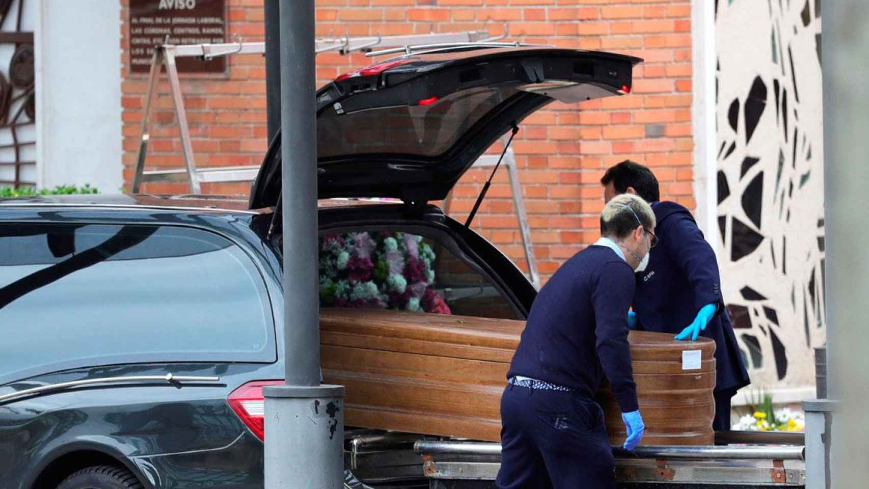 Dos funerarios colocan un féretro en un coche fúnebre en Madrid en plena pandemia / EFE