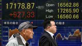 Dos hombres caminan frente a un tablero con los indicadores de la Bolsa de Tokio este jueves / EFE