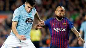 El delantero uruguayo del Celta, Maxi Gómez (i), se dispone a golpear el balón ante el centrocampista chileno del FC Barcelona, Arturo Vidal / EFE