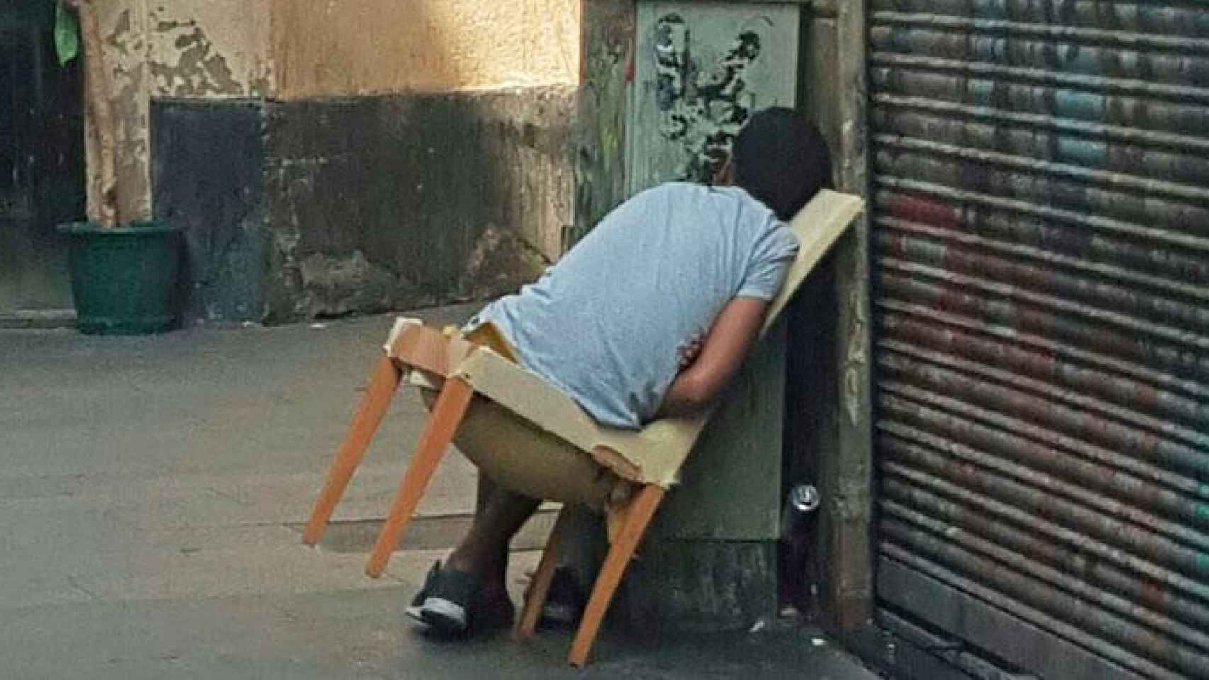Una persona, durmiendo en una silla abandonada en el Raval / CG