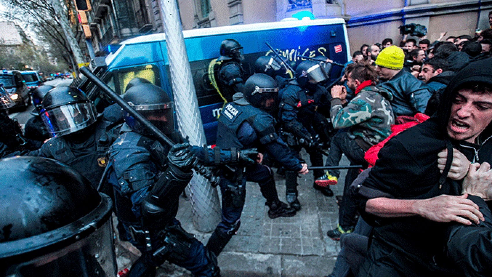 Los Mossos d'Esquadra cargan contra los manifestantes ante la Delegación del Gobierno en Cataluña, con un furgón con una pintada de cómplices al fondo / EFE