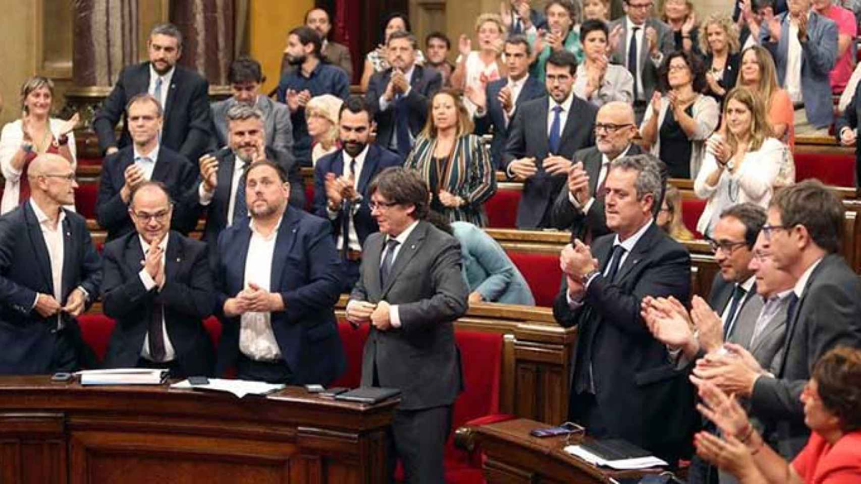 El presidente de la Generalitat, Carles Puigdemont (c), su gobierno, y el resto de diputados celebran la aprobación de la ley del referéndum, con los escaños vacios de PSC, Ciudadanos y PPC en el Parlament / EFE
