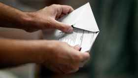 Una persona introduciendo una papeleta electoral dentro del sobre para votar / EUROPA PRESS