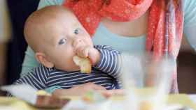 Un bebé mientras come un trozo de pan / THINKSTOCK