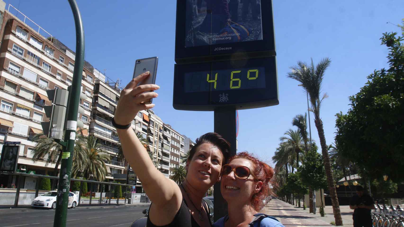 Dos mujeres se sacan un 'selfie' frente a un termómetro que marca 46 grados / EFE
