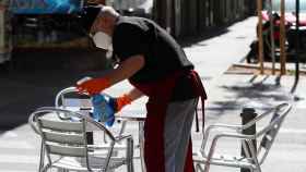 Un camarero desinfecta las sillas de la terraza de un bar en Cataluña / EP