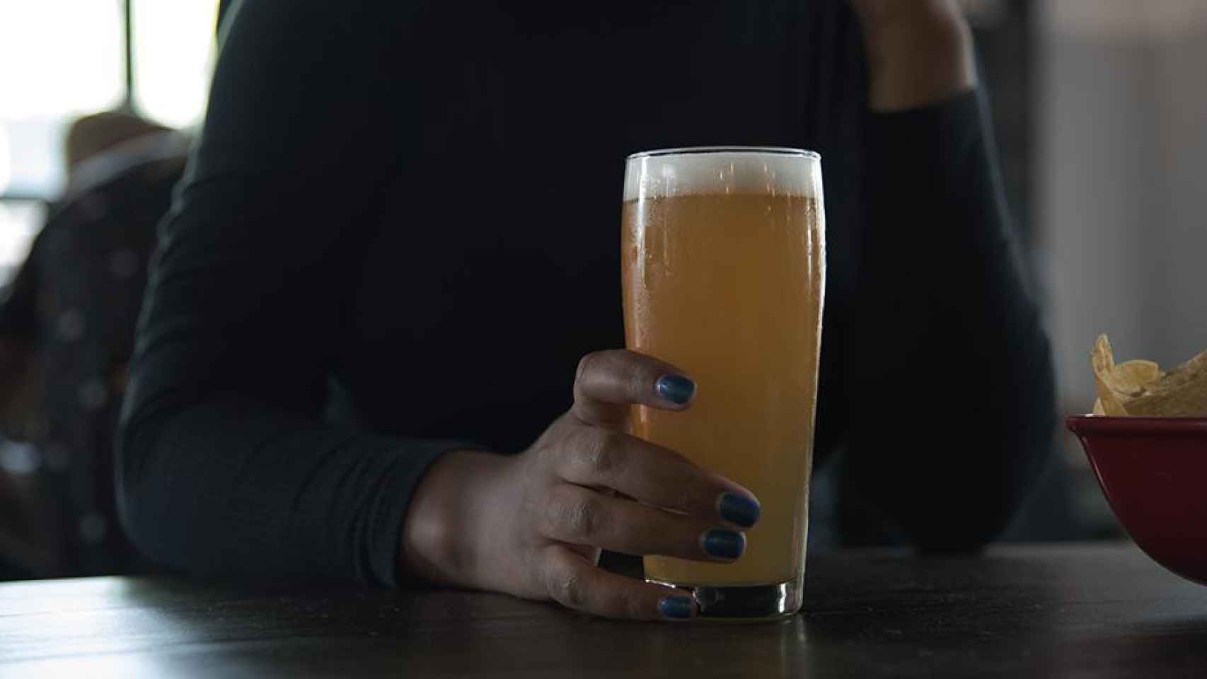 Mujer tomando una cerveza en un bar / PEXELS