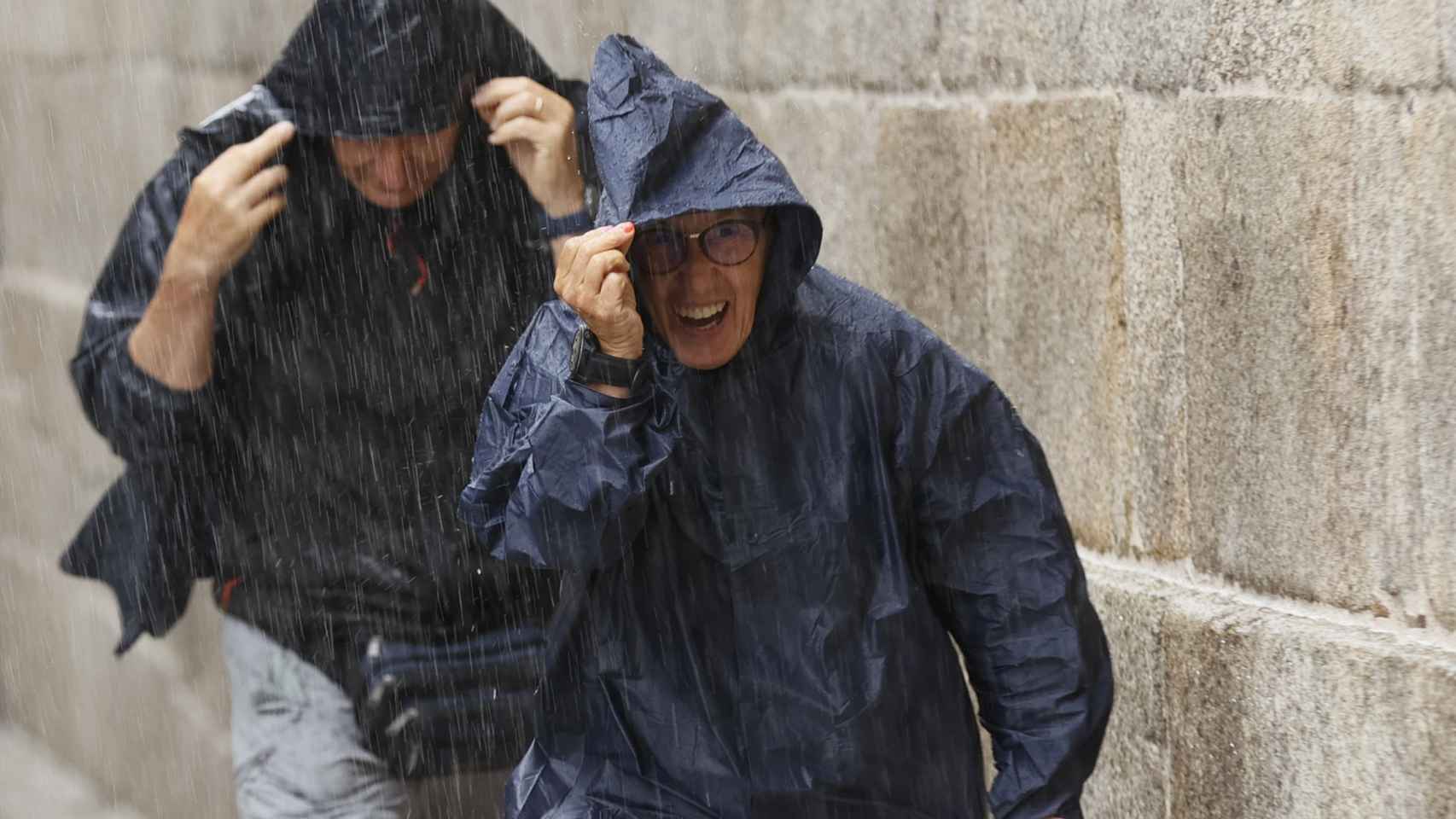 Turistas y peregrinos corren para resguardarse de la lluvia, este martes en Santiago de Compostela, Galicia / EFE