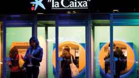 Clientes de CaixaBank sacando dinero en efectivo de cajeros de la entidad / EFE