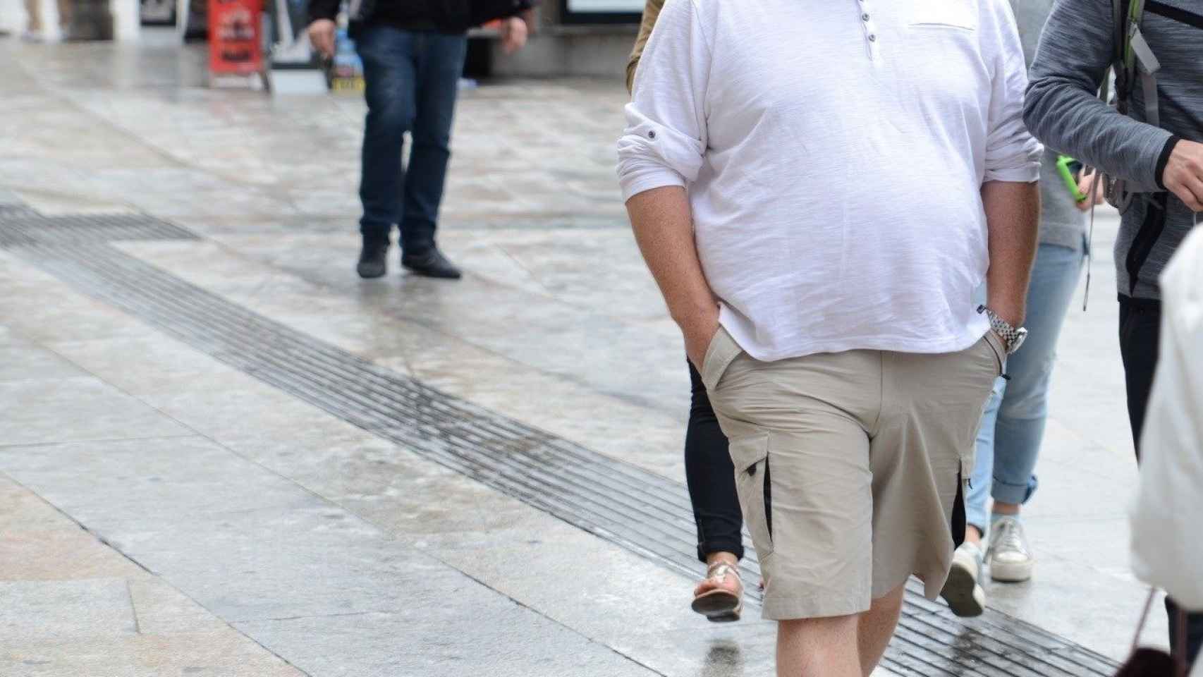Un hombre de cierta edad con sobrepeso paseando por una calle de la capital de España