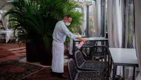 Imagen de un camarero protegido contra el Covid-19 limpiando una mesa / EP