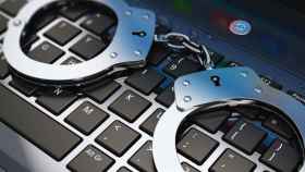 Imagen de un teclado de ordenador con unas manillas encima que ilustra los delitos informáticos que se producen diariamente en internet.