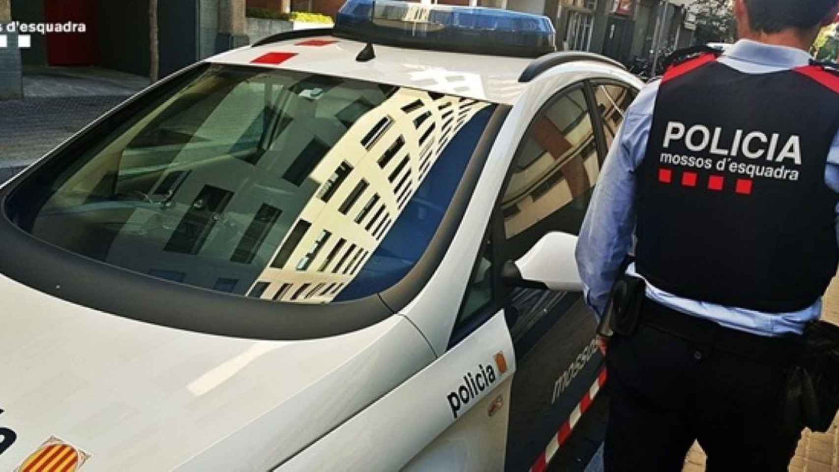 Un mosso pasa junto al vehículo policial / EP