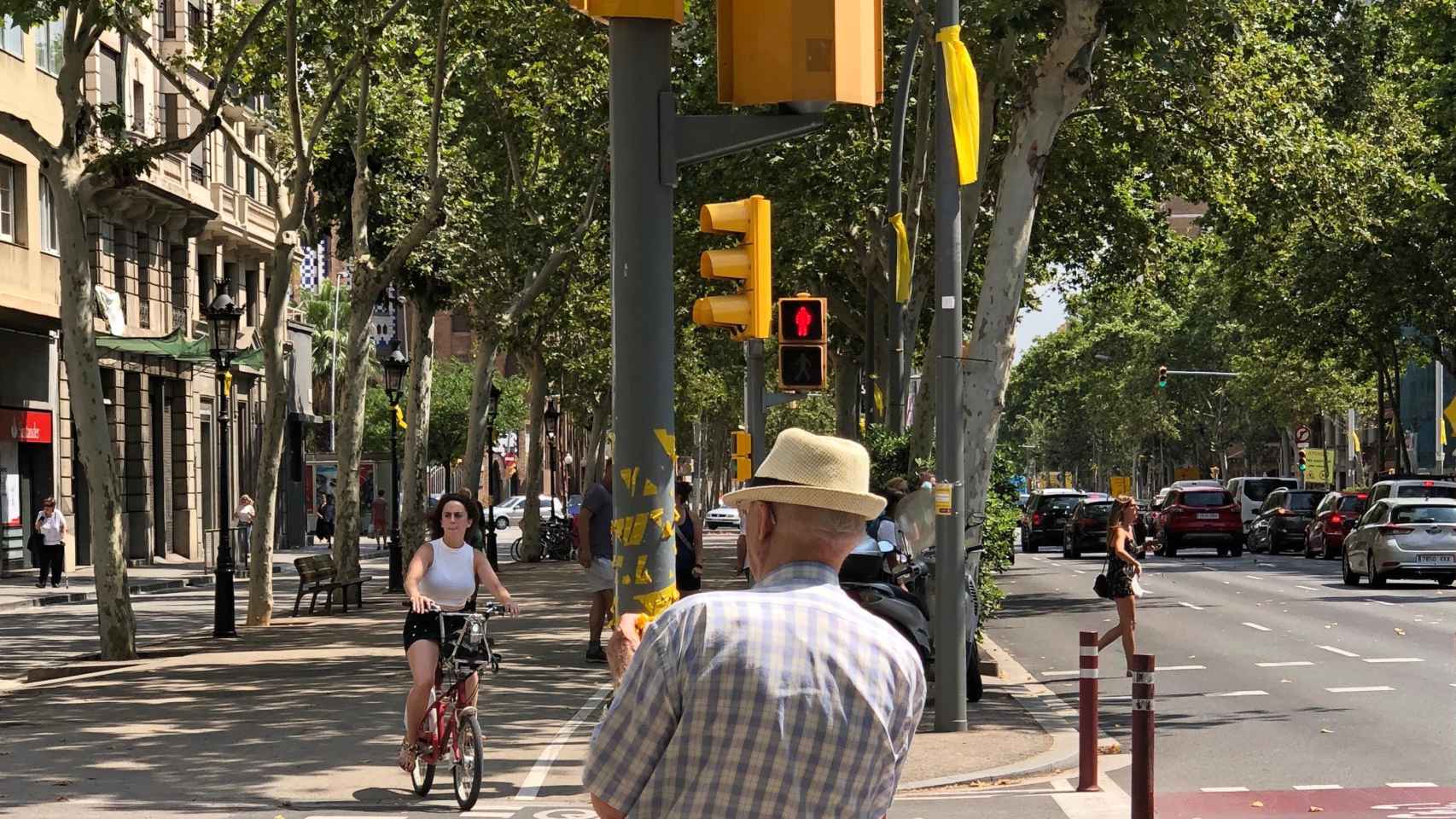 Un ciudadano arranca una a una las cintas amarillas que a modo de lazos alguien ha pegado en un semáforo / CG