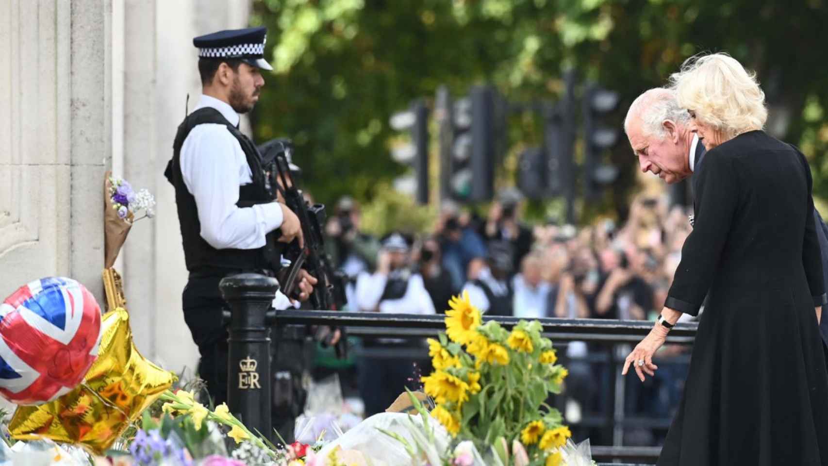 El rey Carlos III y Camilla, la reina consorte, observan los tributos florales a su llegada al Palacio de Buckingham en Londres / EFE