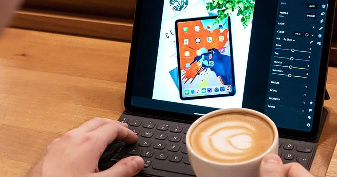 Persona trabajando en diseño gráfico en una 'tablet' mientras bebe un café / UNSPLASH