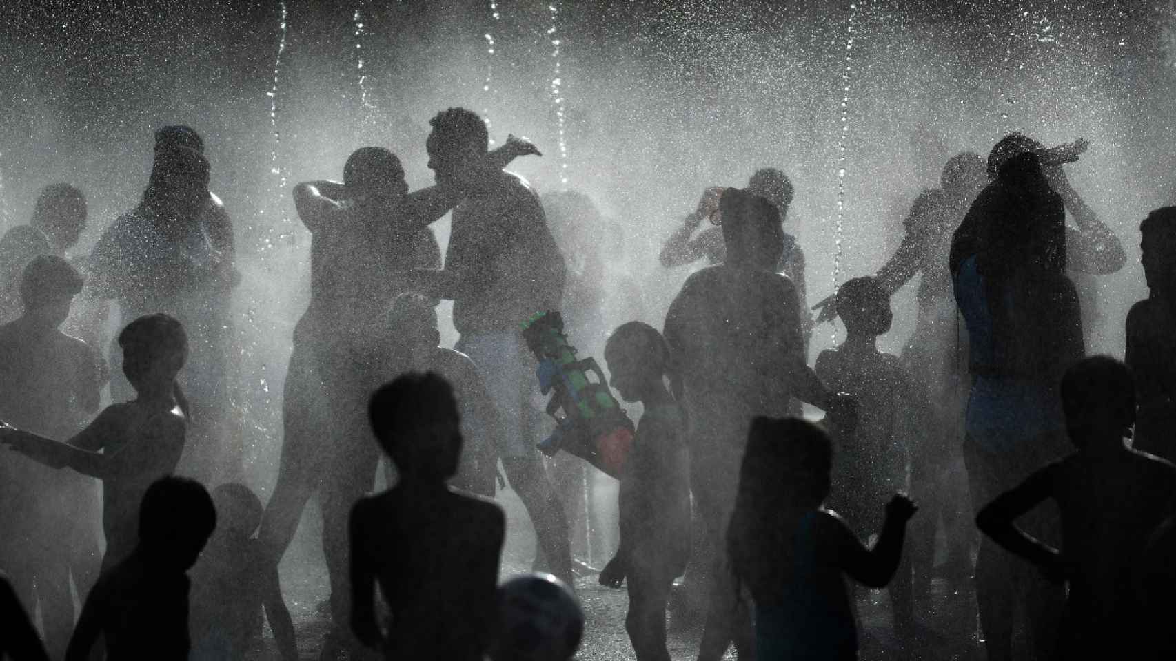Varias personas se refugian en unos chorros de agua durante la ola de calor / EUROPAPRESS