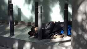 Una persona sintecho duerme entre bolardos, uno de los elementos de la arquitectura hostil que denuncia Arrels / EUROPA PRESS