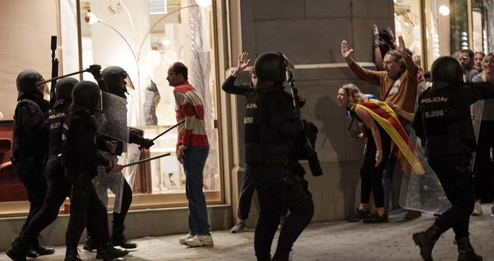Policías y manifestantes ante un escaparate roto en el centro de Barcelona / EFE