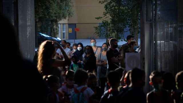 Alumnos y padres con mascarillas para evitar el contagio por Covid esperan ante la puerta de un colegio en Cataluña / EP