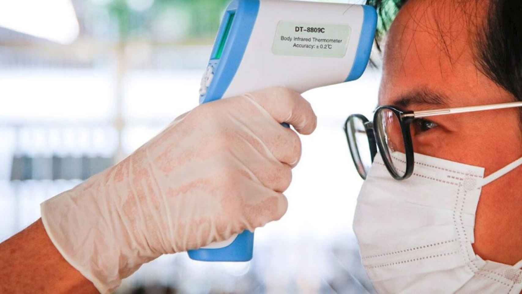 Un hombre mientras le miden la temperatura corporal durante el brote de coronavirus / EFE