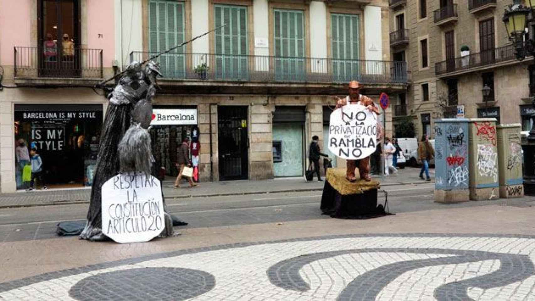 Dos estatuas humanas con carteles reivindicativos en La Rambla de Barcelona / CG