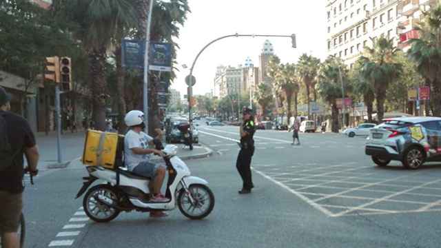 Una agente de policía dirige el tráfico junto a un semáforo apagado durante el corte de luz del 31 de julio en el cruce Casp y Marina de Barcelona / CG