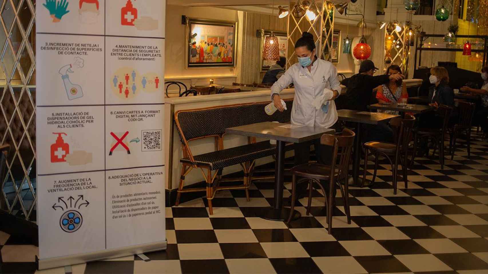 Una trabajadora desinfecta una mesa en un restaurante antes de servir comidas / EP