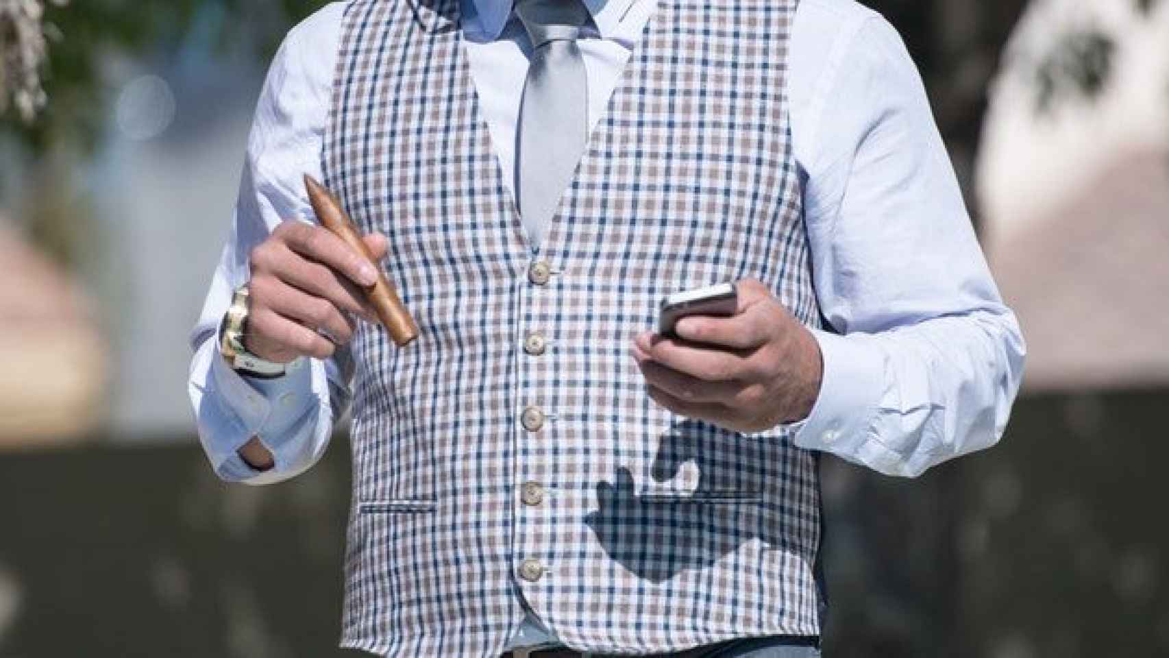 Un hombre adinerado, con su móvil y puro en mano