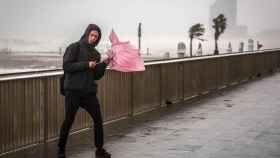 Un joven sujeta su paraguas frente a las fuertes rachas de viento que soplan en el paseo marítimo de Barcelona / EP