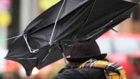 Un viandante sujeta un paraguas roto por las fuertes rachas de viento / EFE